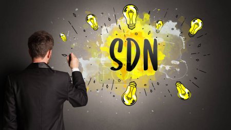 Photo for Businessman drawing colorful light bulb with SDN abbreviation, new technology idea concept - Royalty Free Image