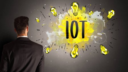 Foto de Hombre de negocios dibujo bombilla de colores con abreviatura IOT, concepto de idea de nueva tecnología - Imagen libre de derechos