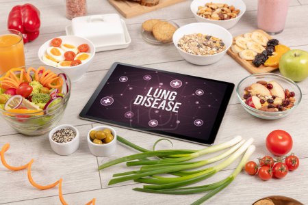 Téléchargez les photos : LUNG DISEASE concept en comprimé PC avec des aliments sains autour, vue du dessus - en image libre de droit