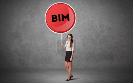 Téléchargez les photos : Jeune homme d'affaires holdig panneau de signalisation avec l'abréviation BIM, concept de solution technologique - en image libre de droit