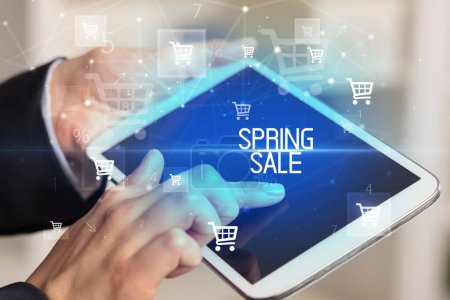 Photo for Young person makes a purchase through online shopping application with SPRING SALE inscription - Royalty Free Image