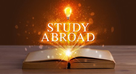 Photo for STUDY ABROAD inscription coming out from an open book, educational concept - Royalty Free Image