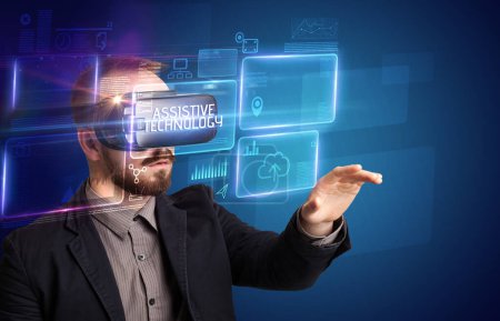 Téléchargez les photos : Homme d'affaires regardant à travers des lunettes de réalité virtuelle avec inscription ASSISTIVE TECHNOLOGY, nouveau concept technologique - en image libre de droit