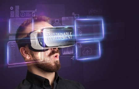 Téléchargez les photos : Homme d'affaires regardant à travers des lunettes de réalité virtuelle avec inscription DEVELOPPEMENT DURABLE, concept de nouvelle technologie - en image libre de droit