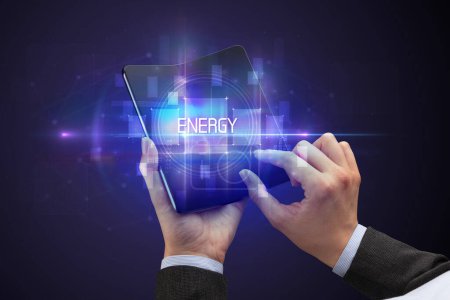 Foto de Empresario sosteniendo un smartphone plegable con inscripción ENERGY, concepto de nueva tecnología - Imagen libre de derechos