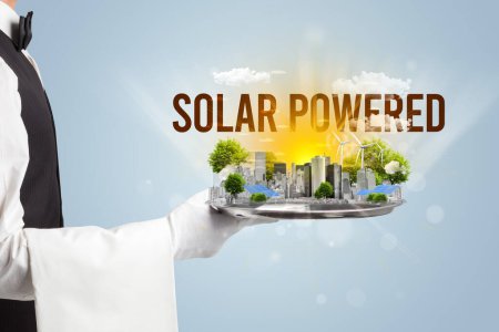 Foto de Camarero sirviendo eco ciudad con inscripción SOLAR POWERED, concepto de energía renovable - Imagen libre de derechos