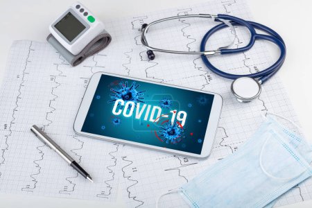 Foto de Tablet PC y herramientas médicas en superficie blanca con inscripción COVID-19, concepto pandémico - Imagen libre de derechos