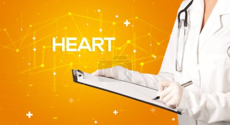 Téléchargez les photos : Le médecin remplit le dossier médical avec l'inscription HEART, concept médical - en image libre de droit