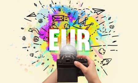 Téléchargez les photos : Gros plan d'une main tenant un appareil photo numérique avec dessin abstrait et inscription EUR - en image libre de droit