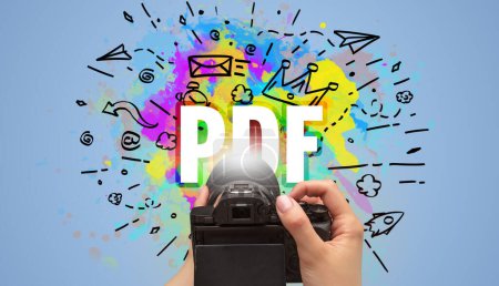 Photo for Close-up of a hand holding digital camera with abstract drawing and PDF inscription - Royalty Free Image
