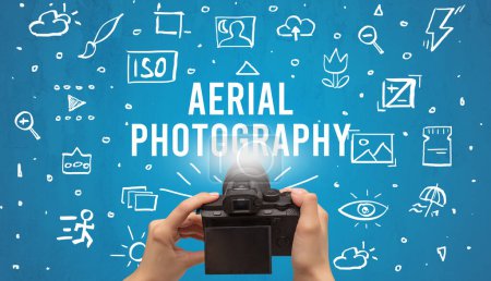 Photo for Hand taking picture with digital camera and AERIAL PHOTOGRAPHY inscription, camera settings concept - Royalty Free Image