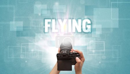 Téléchargez les photos : Gros plan d'un appareil photo numérique à main avec inscription FLYING, concept de voyage - en image libre de droit