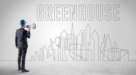 Téléchargez les photos : Homme d'affaires en casque rigide tenant un plan directeur avec inscription Greenhouse, concept d'ingénierie et d'architecture - en image libre de droit