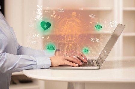 Photo for Doctor working on laptop with healthcare icons coming out from it, healthcare concept - Royalty Free Image