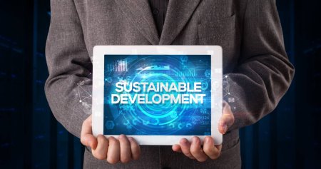 Photo for Young business person working on tablet and shows the inscription: SUSTAINABLE DEVELOPMENT, business concept - Royalty Free Image