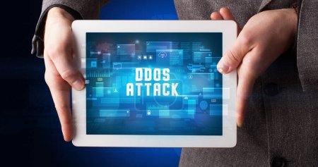 Photo for Young business person working on tablet and shows the digital sign: DDOS ATTACK - Royalty Free Image