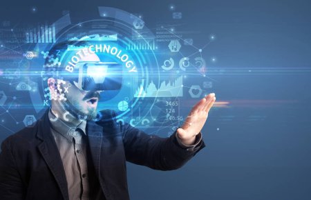 Foto de Hombre de negocios mirando a través de gafas de realidad virtual con inscripción BIOTECHNOLOGY, concepto de tecnología innovadora - Imagen libre de derechos