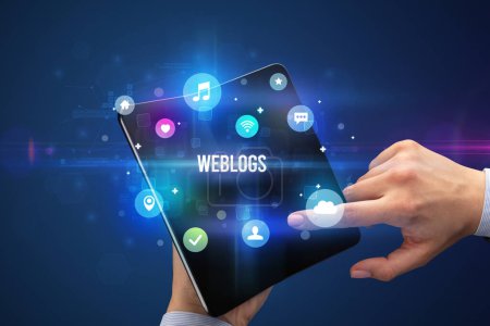 Foto de Empresario sosteniendo un smartphone plegable con inscripción WEBLOGS, concepto de redes sociales - Imagen libre de derechos