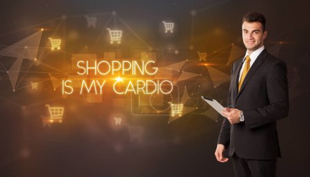 Photo for Businessman with shopping cart icons and SHOPPING IS MY CARDIO inscription, online shopping concept - Royalty Free Image