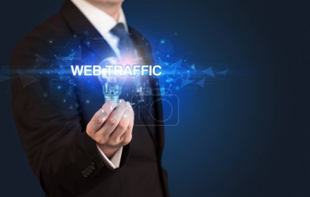 Photo for Businessman holding light bulb with WEB TRAFFIC inscription, innovative technology concept - Royalty Free Image