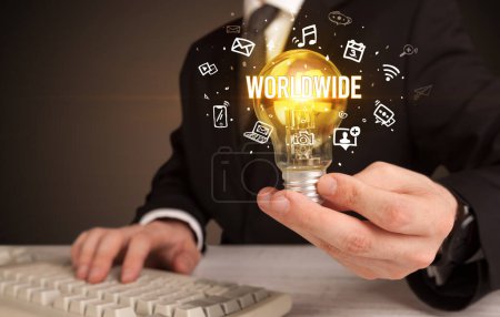 Téléchargez les photos : Homme d'affaires tenant une ampoule avec inscription WORLDWIDE, concept de médias sociaux - en image libre de droit