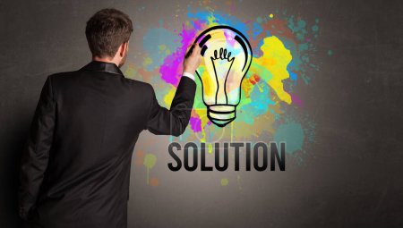 Téléchargez les photos : Homme d'affaires dessin ampoule colorée avec inscription SOLUTION sur mur en béton texturé, nouveau concept d'idée d'entreprise - en image libre de droit