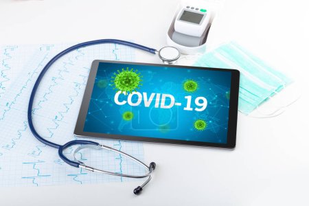 Foto de Vista de cerca de una tableta PC con inscripción COVID-19, concepto de microbiología - Imagen libre de derechos