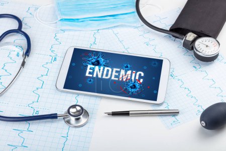 Foto de Tablet PC y herramientas médicas en superficie blanca con inscripción ENDEMIC, concepto pandémico - Imagen libre de derechos