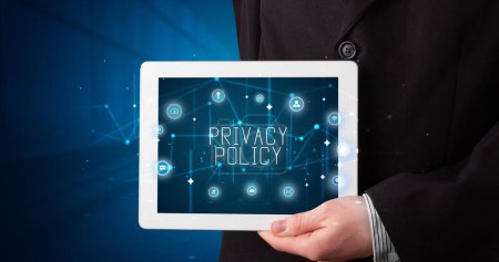 Photo for Young business person working on tablet and shows the digital sign: PRIVACY POLICY - Royalty Free Image