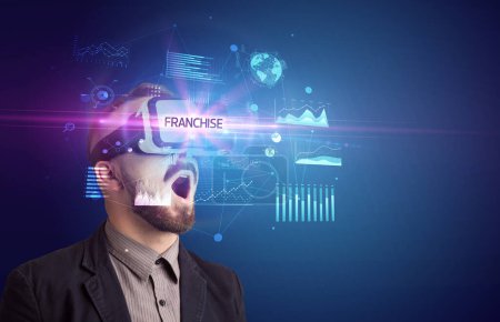 Photo for Businessman looking through Virtual Reality glasses with FRANCHISE inscription, new business concept - Royalty Free Image