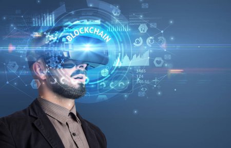 Foto de Hombre de negocios mirando a través de gafas de realidad virtual con inscripción BLOCKCHAIN, concepto de tecnología innovadora - Imagen libre de derechos