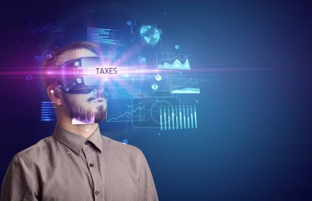 Foto de Hombre de negocios mirando a través de gafas de realidad virtual con inscripción TAXES, nuevo concepto de negocio - Imagen libre de derechos
