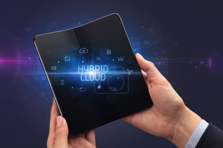 Foto de Empresario sosteniendo un smartphone plegable con inscripción HYBRID CLOUD, concepto de ciberseguridad - Imagen libre de derechos