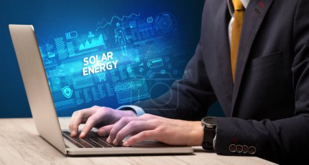 Foto de Empresario trabajando en laptop con inscripción SOLAR ENERGY, concepto de cibertecnología - Imagen libre de derechos