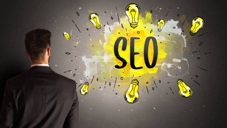 businessman drawing colorful light bulb with SEO abbreviation, new technology idea concept