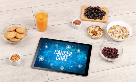 Téléchargez les photos : CANCER CURE concept en comprimé PC avec des aliments sains autour, vue du dessus - en image libre de droit