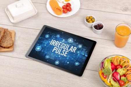 Foto de Concepto PULSA IRREGULAR en la tableta PC con alimentos saludables alrededor, vista superior - Imagen libre de derechos