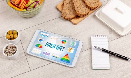 Foto de Alimento orgánico y tableta pc que muestra la inscripción DASH DIET, composición nutricional saludable - Imagen libre de derechos