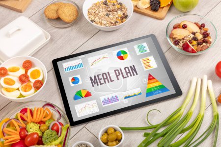 Photo for Organic food and tablet pc showing MEAL PLAN inscription, healthy nutrition composition - Royalty Free Image