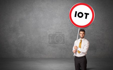 Photo for Young business person holdig traffic sign with IOT abbreviation, technology solution concept - Royalty Free Image