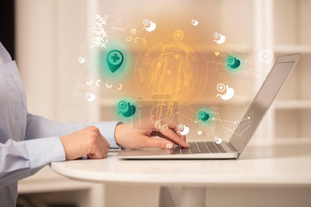 Foto de Médico trabajando en el ordenador portátil con los iconos de la ubicación del hospital que sale de ella, concepto de salud - Imagen libre de derechos