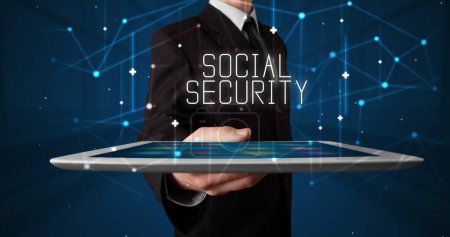 Photo for Young business person working on tablet and shows the digital sign: SOCIAL SECURITY - Royalty Free Image