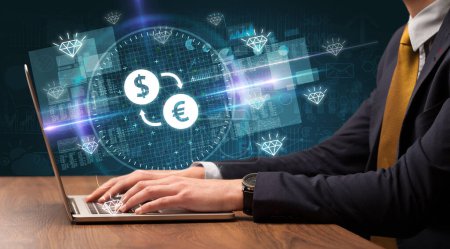 Téléchargez les photos : Main d'œuvre d'affaires travaillant en bourse avec dollar - icônes de la bourse de l'euro sortant de l'écran d'ordinateur portable - en image libre de droit