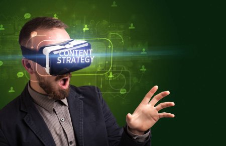 Téléchargez les photos : Homme d'affaires regardant à travers des lunettes de réalité virtuelle avec inscription CONTENT STRATEGY, concept de réseautage social - en image libre de droit