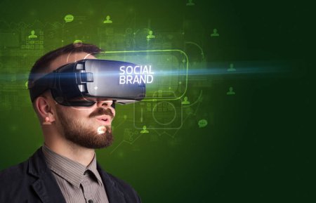 Téléchargez les photos : Homme d'affaires regardant à travers des lunettes de réalité virtuelle avec inscription MARQUE SOCIALE, concept de réseautage social - en image libre de droit