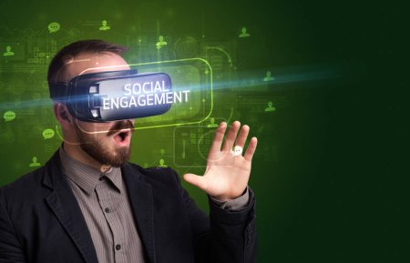 Foto de Hombre de negocios mirando a través de gafas de realidad virtual con inscripción SOCIAL ENGAGEMENT, concepto de redes sociales - Imagen libre de derechos