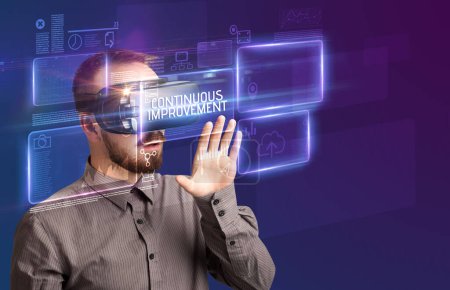 Téléchargez les photos : Homme d'affaires regardant à travers des lunettes de réalité virtuelle avec l'inscription AMÉLIORATION CONTINUE, concept de nouvelle technologie - en image libre de droit