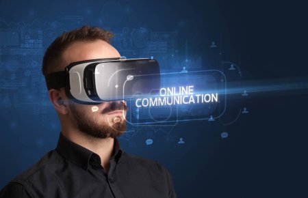 Téléchargez les photos : Homme d'affaires regardant à travers des lunettes de réalité virtuelle avec inscription COMMUNICATION EN LIGNE, concept de réseautage social - en image libre de droit