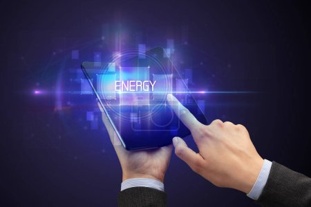Foto de Empresario sosteniendo un smartphone plegable con inscripción ENERGY, concepto de nueva tecnología - Imagen libre de derechos