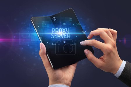 Foto de Empresario sosteniendo un smartphone plegable con inscripción PROXY SERVER, concepto de ciberseguridad - Imagen libre de derechos